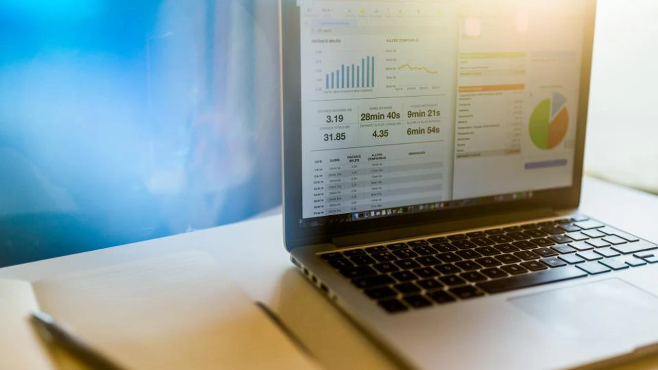 Workspace contabile moderno con MacBook che mostra dashboard finanziaria e taccuino aperto